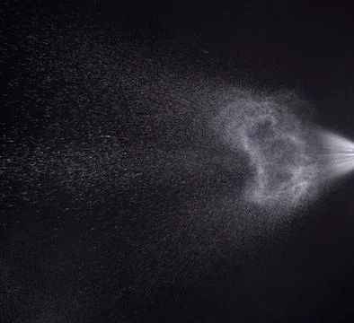 A spray of liquid in a black background. Stock Photos