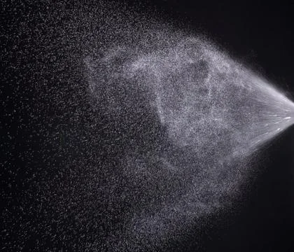 A spray of liquid in a black background. Stock Photos