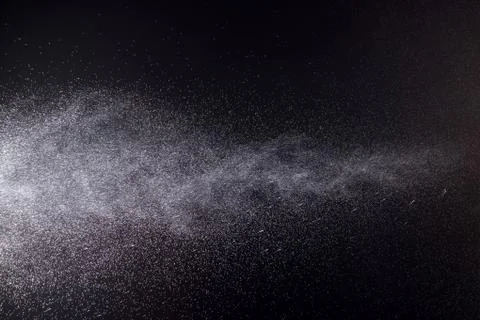 A spray of liquid in a black background. Stock Photos