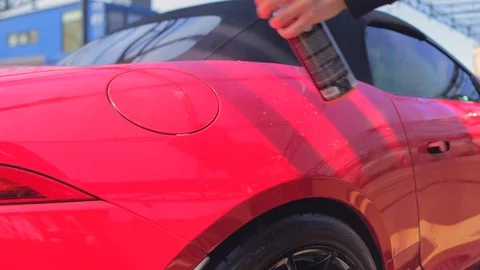 Spray liquid wax on a red convertible and rub with a soft towel to polish Stock Footage 126404972