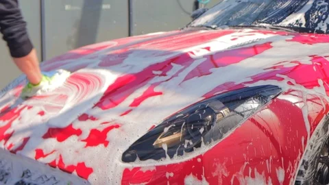Spray a red convertible from a self-washing car with white foam from a foam gun Stock Footage 126404370