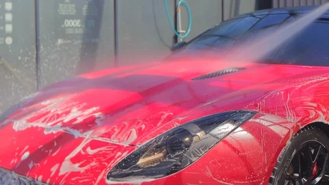 Spray a red convertible from a self-washing car with white foam from a foam gun Stock Footage