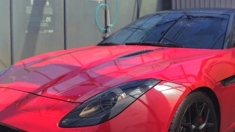 Spray a red convertible from a self-washing car with white foam from a foam gun Stock Footage 126404868