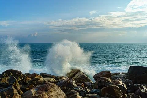 Spray from waves in the air against the background of rocks and sky Stock Photos