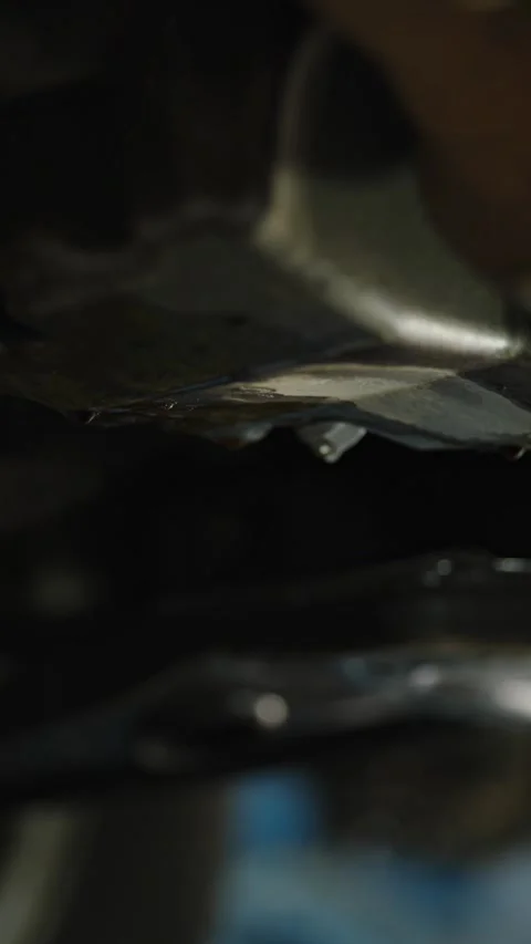Spraying cleaner fluid from red straw onto dirty car oil-pan Stock Footage 337570827