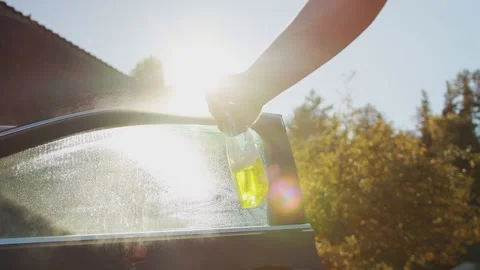 Spraying a cleaning agent to clean door windows in a car against the background Stock Footage 254057387