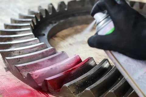 Spraying red dye penetrant or developer on a large industrial gear. 库存照片