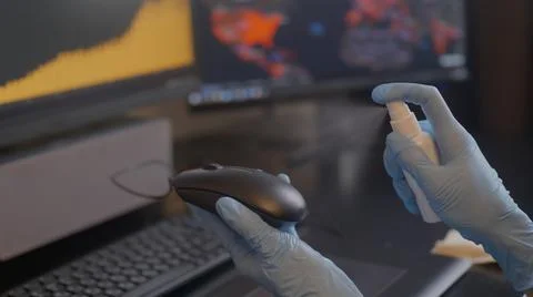 Spraying sanitizer to clean PC mouse,using glowes. Covid-19 disinfection concept Stock Photos