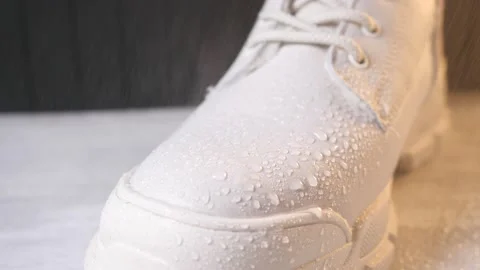 Spraying water on winter shoe protected with waterproof spray Stock Footage 163375648