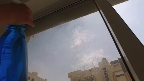 Sprays on the window from the spray gun and wipes with a rag Stock Footage 78215778