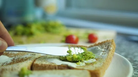 Spread avocado on a toasted bread. Making tasty avocado toast for breakfast Stock-Footage 127960366