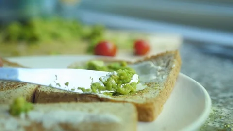 Spread avocado on a toasted bread. Making tasty avocado toast for breakfast Video stock 128168205