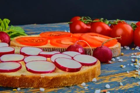 Spread butter on bread with sliced tomatoes and radishes. Fresh snack on natu Fotos de archivo