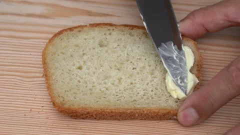 Spread butter on bread. Soft butter spreading on slice of sourdough bread Stock Footage 139682619