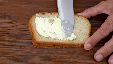 Spread butter on bread. Soft butter spreading on slice of sourdough bread Stock Footage 139758663