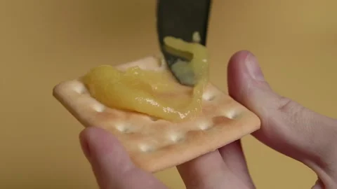 Spread honey on a cookie on a yellow background with a knife. Stock Footage 169153291