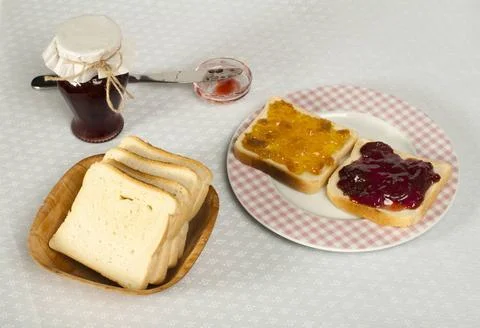 Spread jam on bread Spread jam on bread. Pink checkered plate and jar of j... Stock Photos