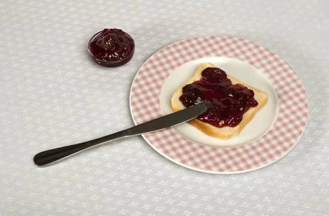 Spread jam on bread Spread jam on bread with knife. Pink checkered plate ,... Stock Photos