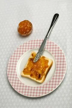 Spread jam on bread Spread jam on bread with knife. Pink checkered plate ,... Stock Photos