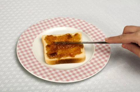 Spread jam on bread Spread jam on bread with knife. Pink checkered plate ,... Stock Photos