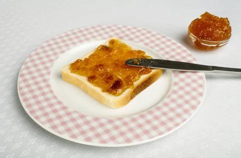 Spread jam on bread Spread jam on bread with knife. Pink checkered plate ,... Stock Photos