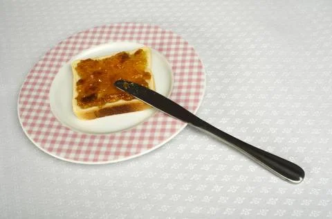 Spread jam on bread Spread jam on bread with knife. Pink checkered plate ,... Stock Photos