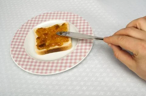 Spread jam on bread Spread jam on bread with knife. Pink checkered plate ,... Stock Photos