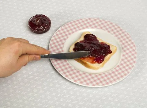 Spread jam on bread Spread jam on bread with knife. Pink checkered plate ,... Stock Photos