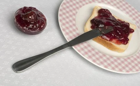 Spread jam on bread Spread jam on bread with knife. Pink checkered plate ,... Stock Photos