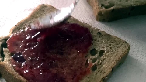 Spread the jam on the breakfast bread with a teaspoon Stock Footage 265094041