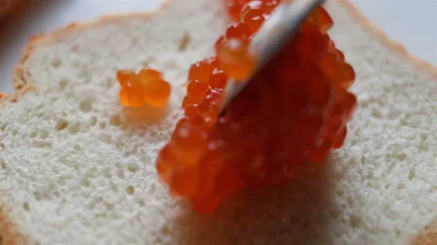 Spread red caviar on white toast bread with a teaspoon. Someone makes a snack (s Stock Footage 108186513
