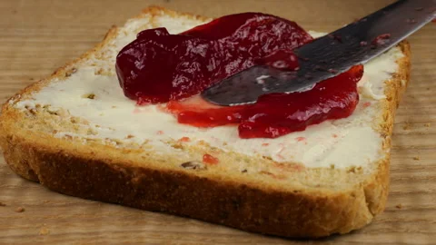 Spread redcurrant jam on a slice of toasted bread with butter using a knife. Video stock 319873737