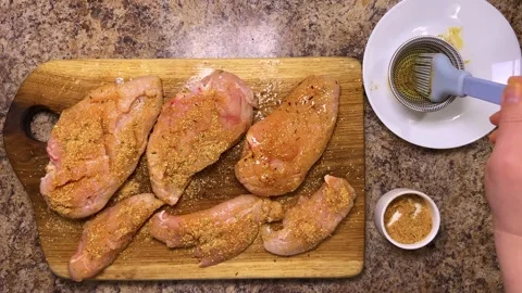 Spread the spices evenly over the chicken breast using a silicone brush. Stock Footage 321152742