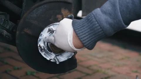 Spreading anti seize graphite grease across wheel hub contact surface during Stock Footage 335368956