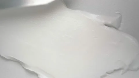 Spreading antiaging squeezed cream jet with spatula on white Stock Footage 170358088