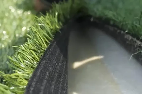 Spreading artificial turf in stadium, rolling out rolls of lawn and leveling. Stock Photos