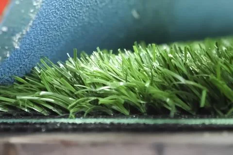 Spreading artificial turf in stadium, rolling out rolls of lawn and leveling. Stock Photos
