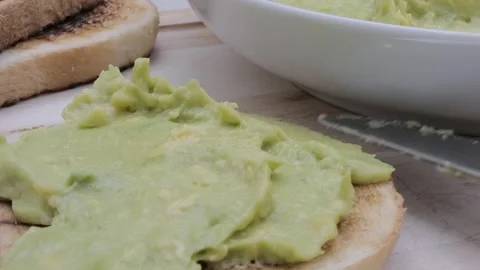 Spreading avocado on a slice of toasted bread Stock Footage 242030584