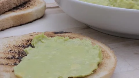 Spreading avocado on a slice of toasted bread Video stock 242030614