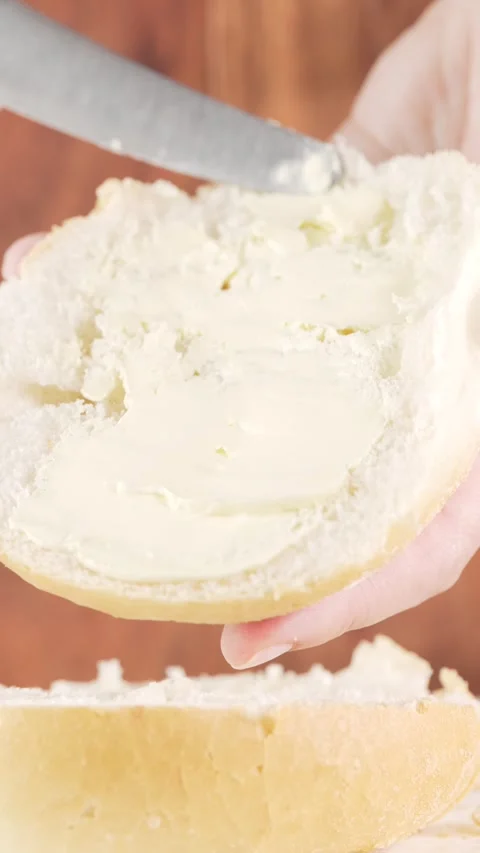 Spreading Butter on Bun Half  Vertical Close-Up Slow Motion on Wooden Blurr.. Stock Footage 312168984