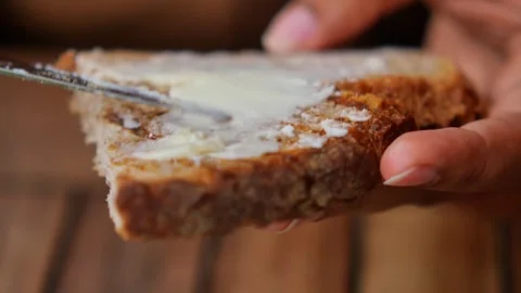 Spreading butter on fresh bread with knife, delicious breakfast preparation. Stock Footage 332140778