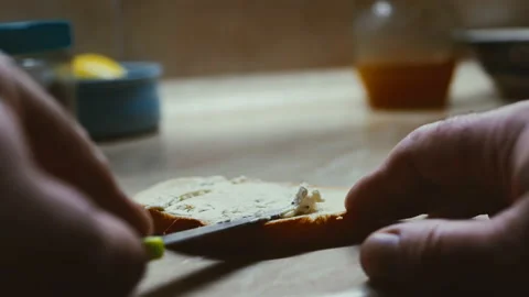 Spreading butter with a knife on a fresh slice of wheat bread, Close-up of a han Stock Footage 161445197
