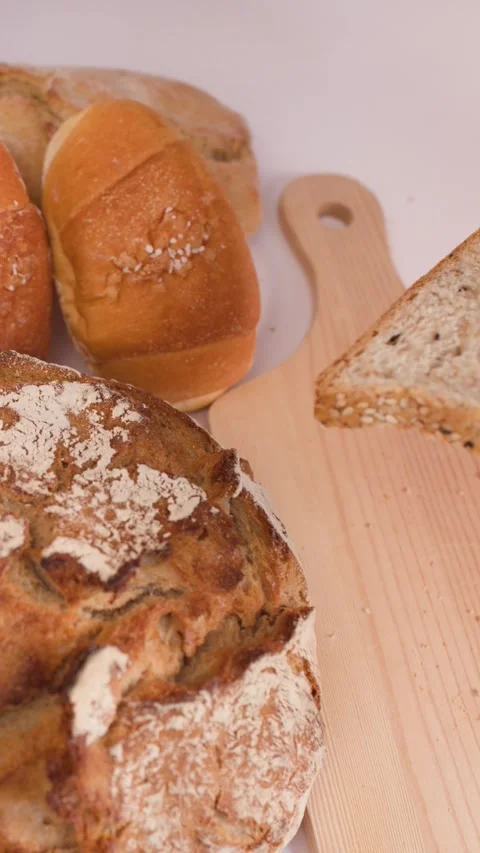 Spreading Butter on Multigrain Bread with Assorted Bakery Loaves Video stock 337767542