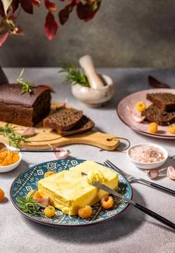 Spreading butter on rustic table with bread and raspberries Stock Photos