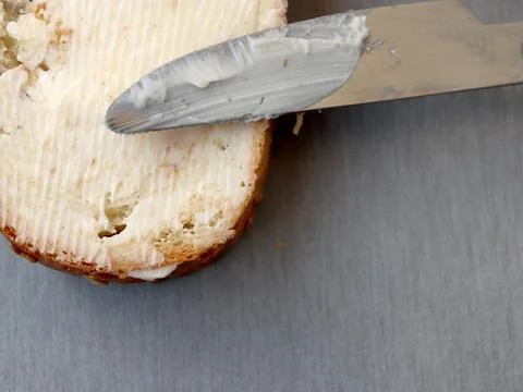 Spreading butter on a slice of bread with a knife on a kitchen surface in the 스톡 사진