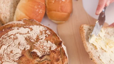 Spreading Butter on Sourdough Bread with Assorted Bakery Items Video stock 337917855