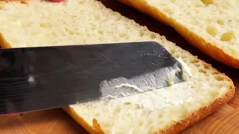 Spreading butter on toasted bread slice with a professional knife for breakfast Stock Footage 325032599