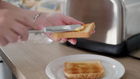 Spreading butter on a toasted slice of bread in a modern kitchen Stock Footage 317006139