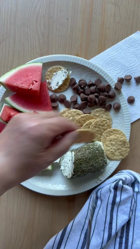Spreading chevre on crackers above cold dinner plate Stock Footage 247663678