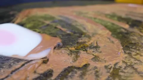 Spreading Chocolate Batter on a Flat Griddle to Make Crepes Stock Footage 345692654
